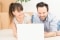 A young couple sitting in a new apartment and uses a laptop. Discuss home repair projects while moving.